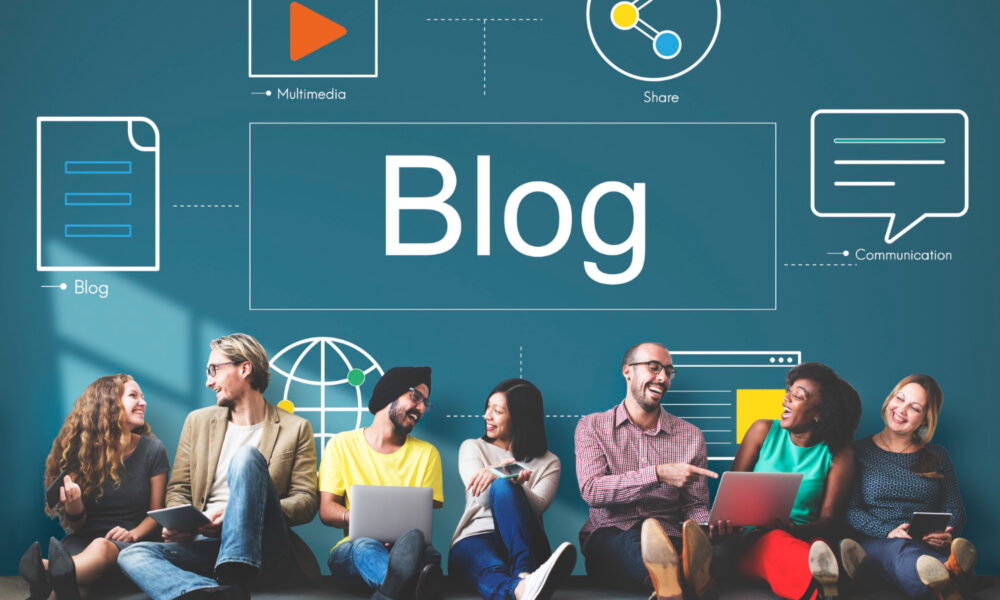 Blog illustration: the word “Blog” alongside icons for multimedia, sharing, and communication, while a group of people sit with laptops and talk.