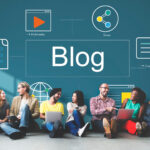 Blog illustration: the word “Blog” alongside icons for multimedia, sharing, and communication, while a group of people sit with laptops and talk.