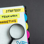 Marketing plan. A notebook with sticky notes labeled “Strategy,” “Teamwork,” and “Marketing.”